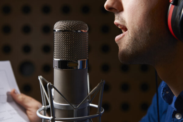 Man,Holding,Notes,And,Talking,Into,Studio,Microphone